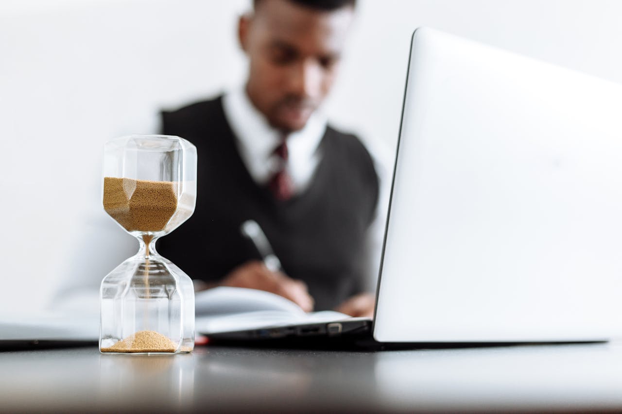 Home Businessman at desk with hourglass indicating time management and daily work routine.