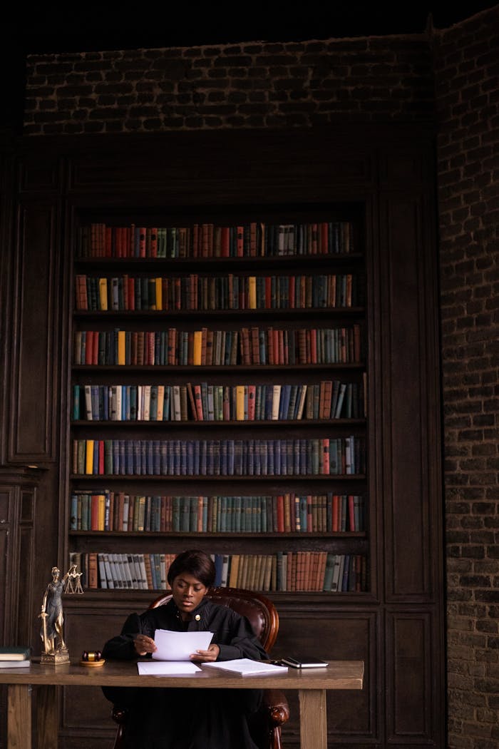 Home Black female judge reading papers at desk in office with bookshelves.