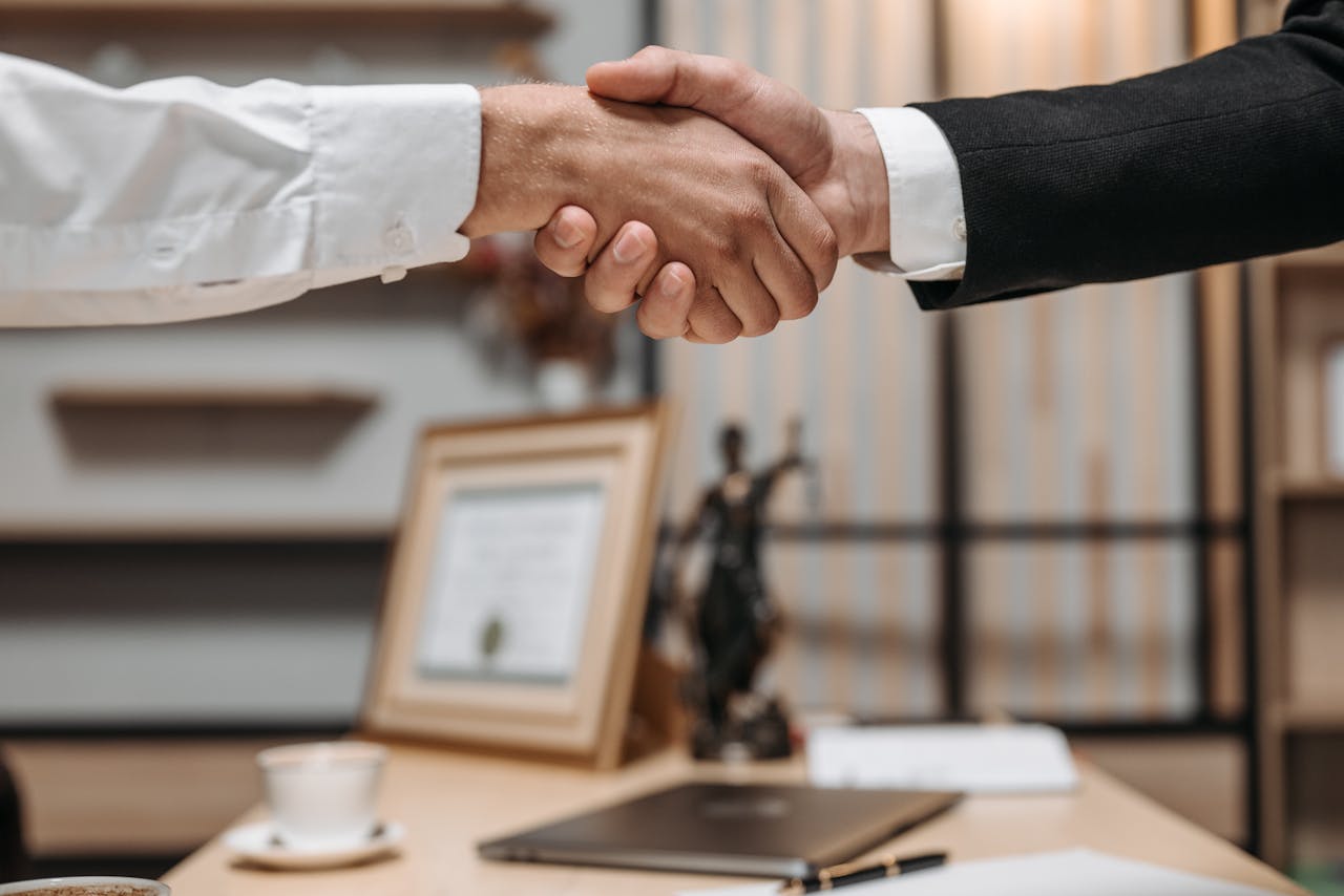 Home Close-up of a handshake between two professionals in a modern office setting, emphasizing partnership and agreement.